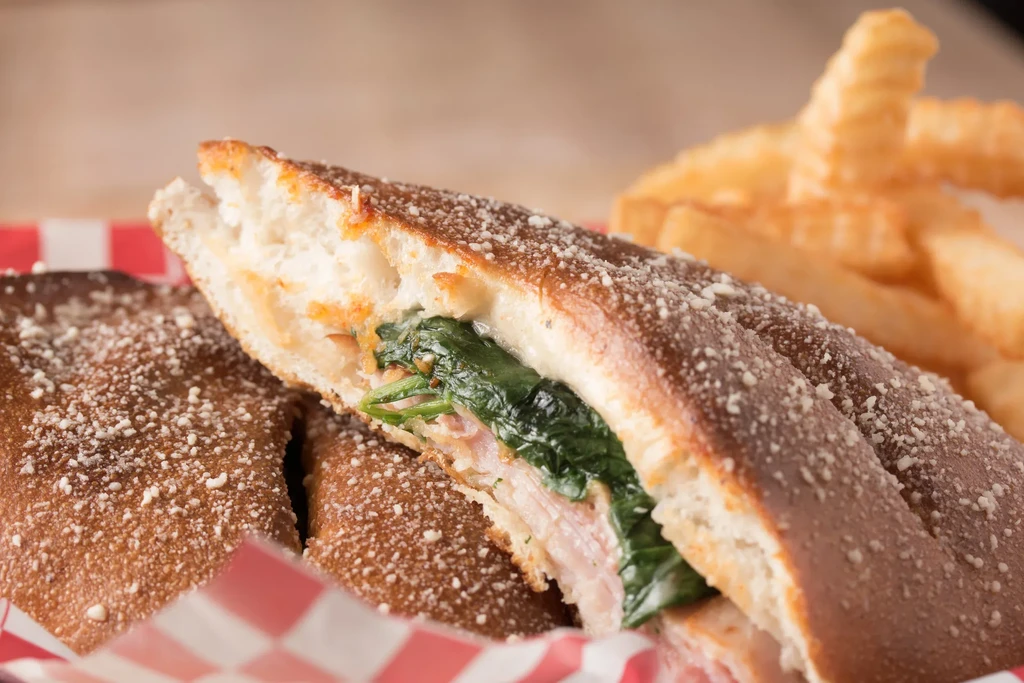 Savory pastry or calzone, cut in half, with fries in background.