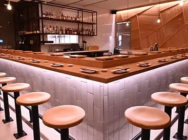 Modern sushi bar interior with a U-shaped counter and bar stools.