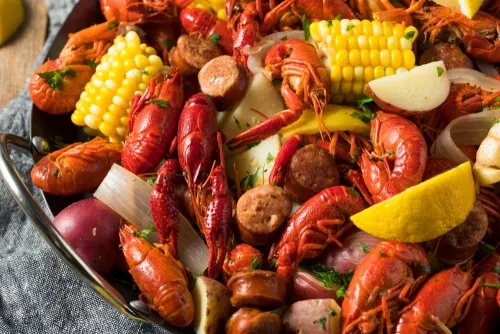 Close-up overhead shot of a crawfish boil with corn, potatoes, and sausage.