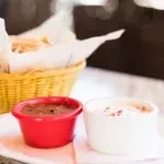 Two ramekins, one red and one white, on a white napkin.