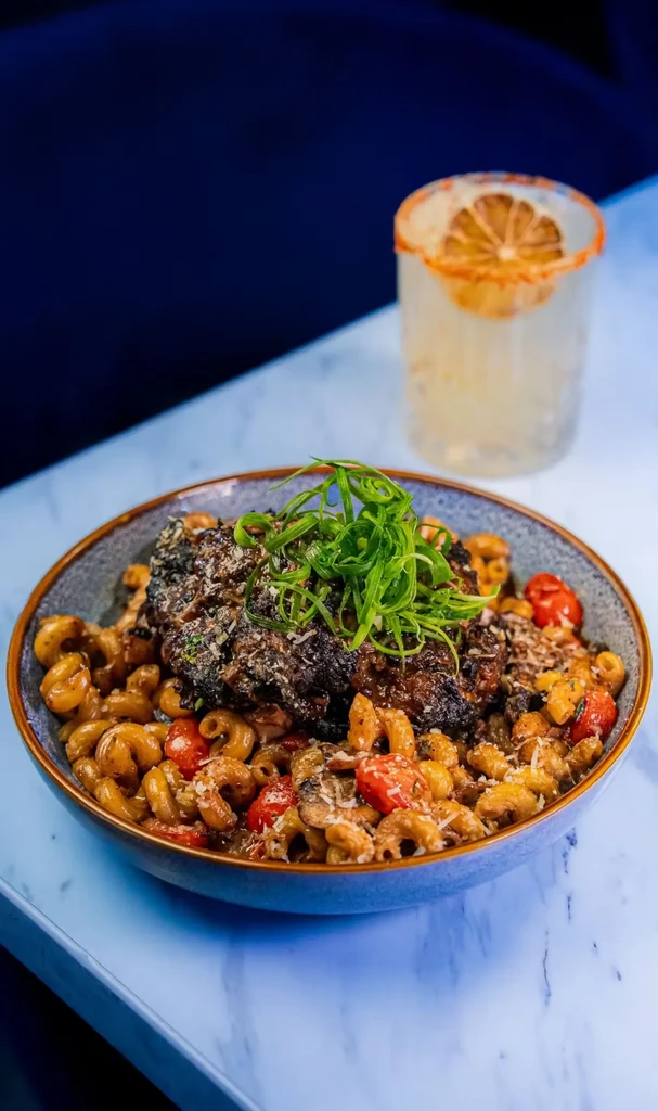 Pasta with braised meat, tomatoes, cheese, and a cocktail.