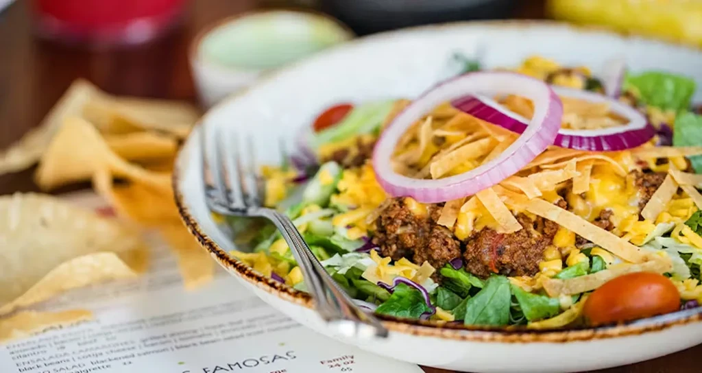 Close-up of a vibrant taco salad in a white bowl with a fork.