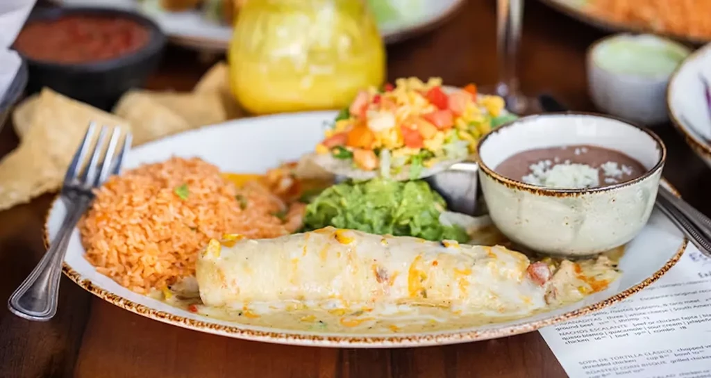 Plate of Mexican food: enchilada, rice, guacamole, beans, and tostada.