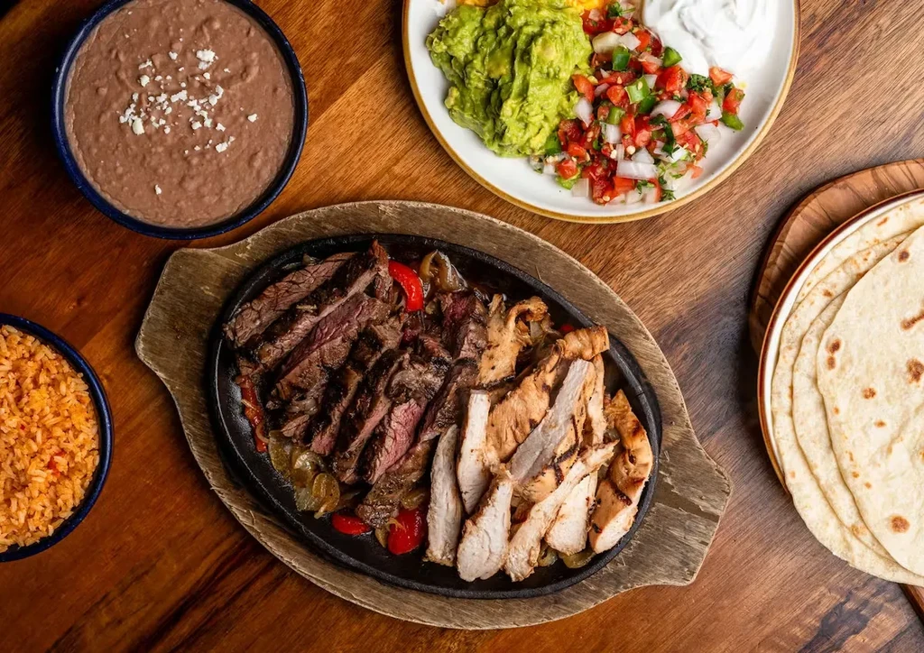 Top-down view of a Mexican fajita meal on a wooden table.