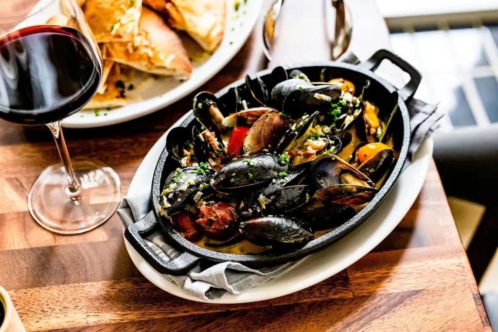 Cast iron dish of mussels, clams, and chorizo with red wine.