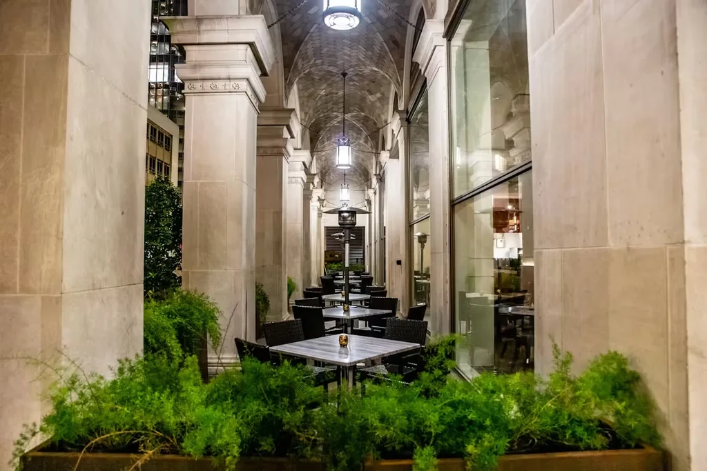 An elegant outdoor dining area with tables, chairs, and stone pillars.