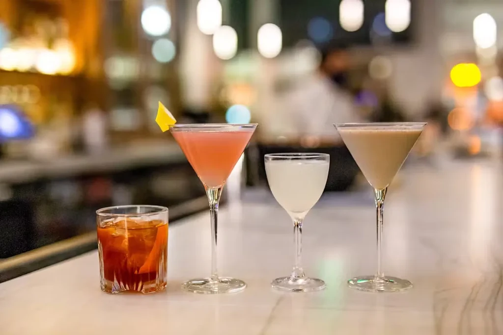 Four cocktails on a marble bar counter, with a blurred background.