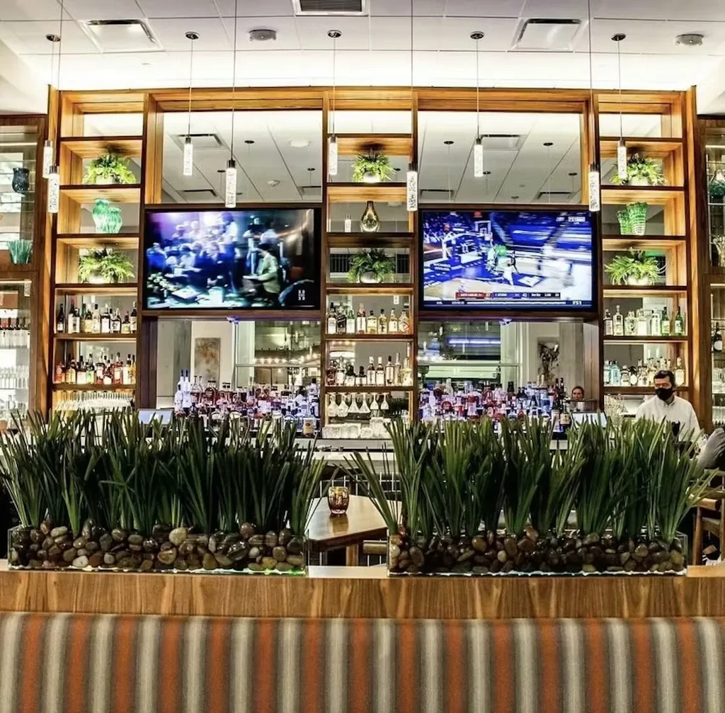 Well-stocked bar with two TVs, one showing basketball.