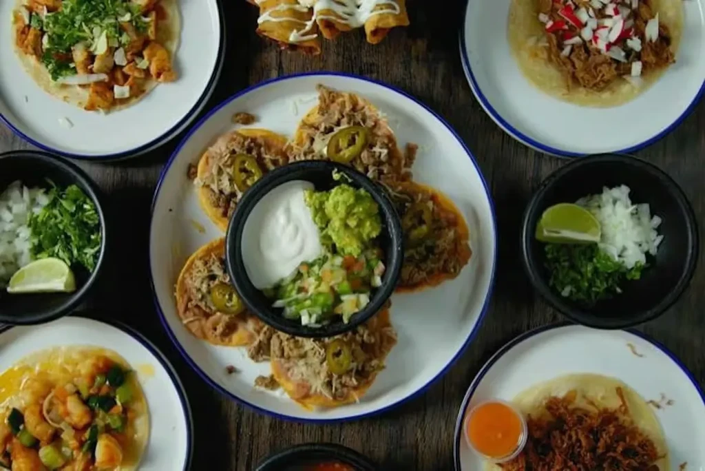 Overhead shot of multiple plates of Mexican tacos and tostadas.