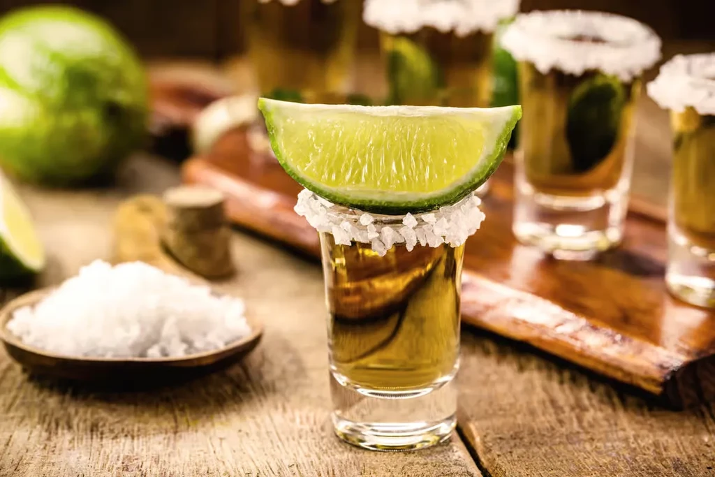 Tequila shot with lime and salt, other shots in background.