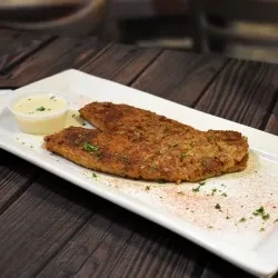 Two seasoned fish fillets on a white plate with sauce.