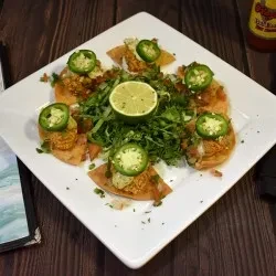 Six tostadas with chicken, sauce, jalapeños, lettuce, and lime.