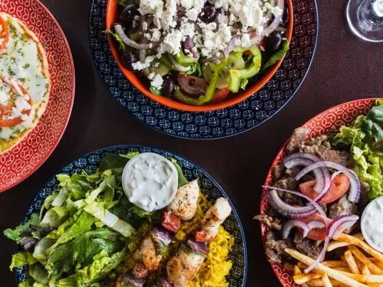 Overhead view of a table with four Greek and Mediterranean dishes.