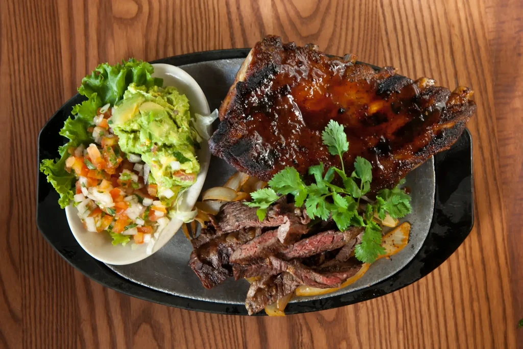 Overhead shot of ribs, steak, pico de gallo, and guacamole.