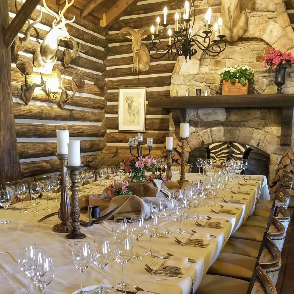 Rustic dining room with set table, candelabras, and mounted animal heads.
