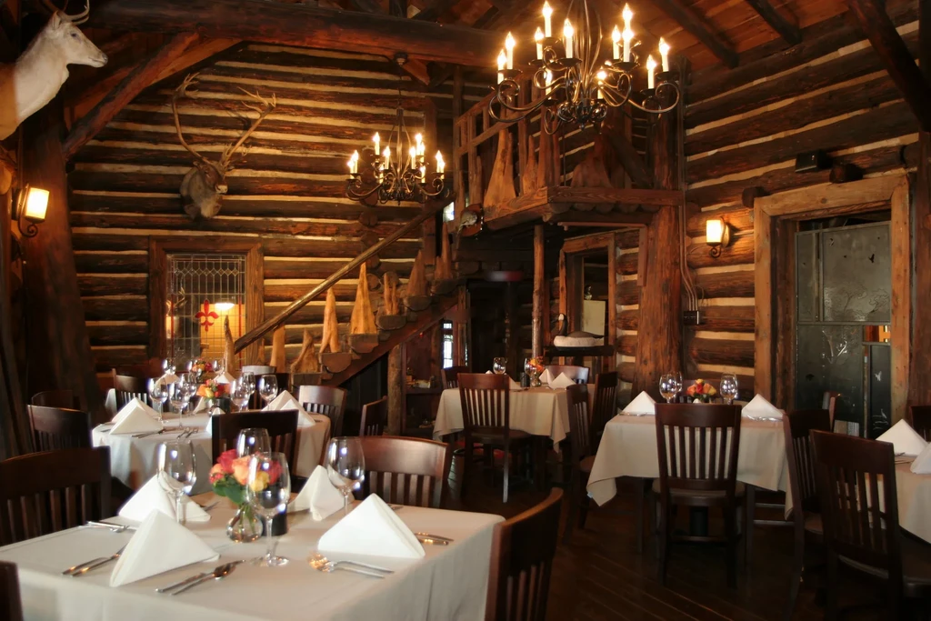 Rustic restaurant interior with set tables, chandeliers, and taxidermy.