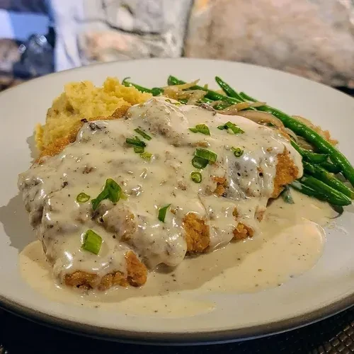 Fried chicken with gravy, mashed potatoes, and green beans.