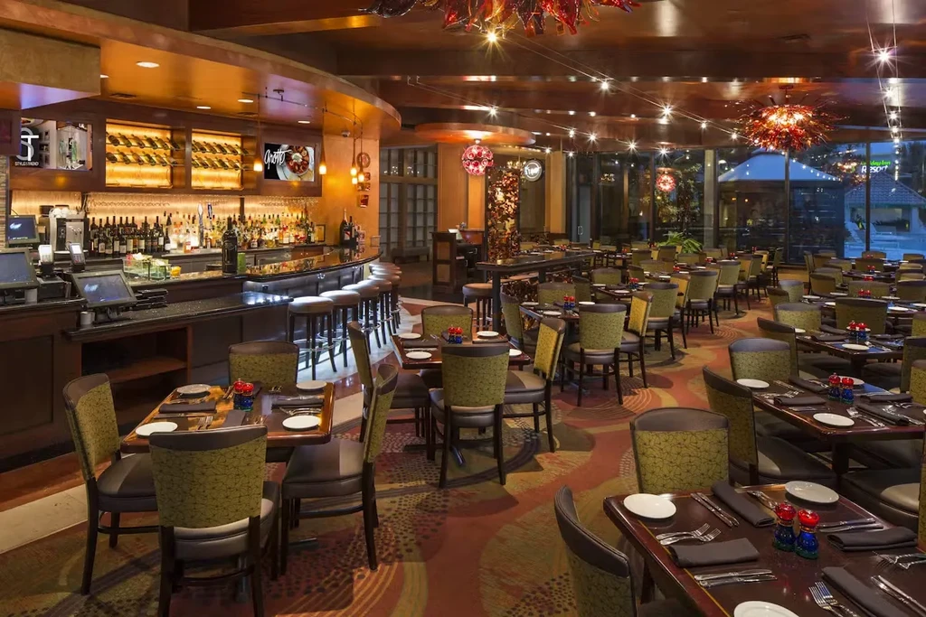 Upscale restaurant interior with dining tables, bar, and patterned carpet.