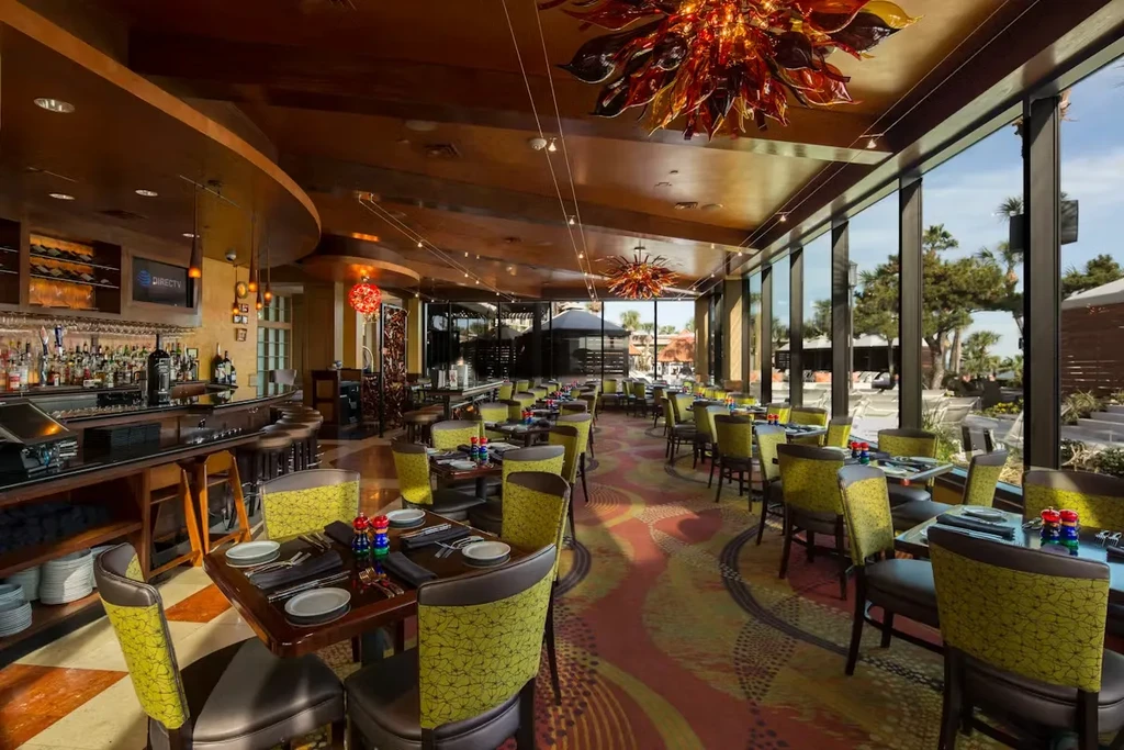 Empty restaurant interior with patterned carpet and lime green chairs.