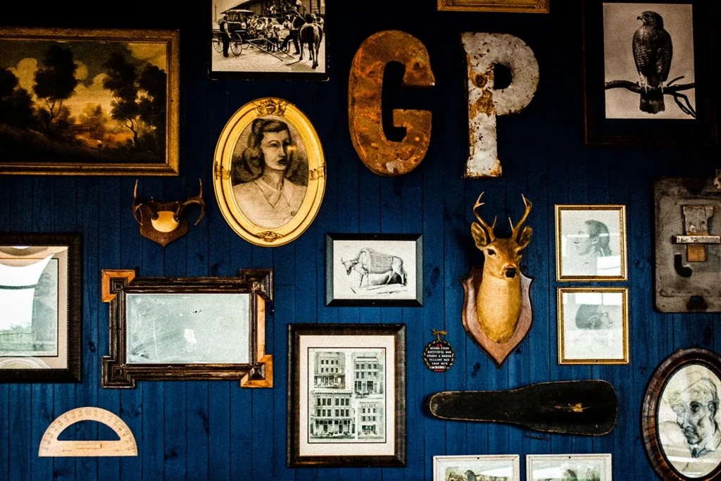 Dark blue wall adorned with eclectic framed art and deer head.
