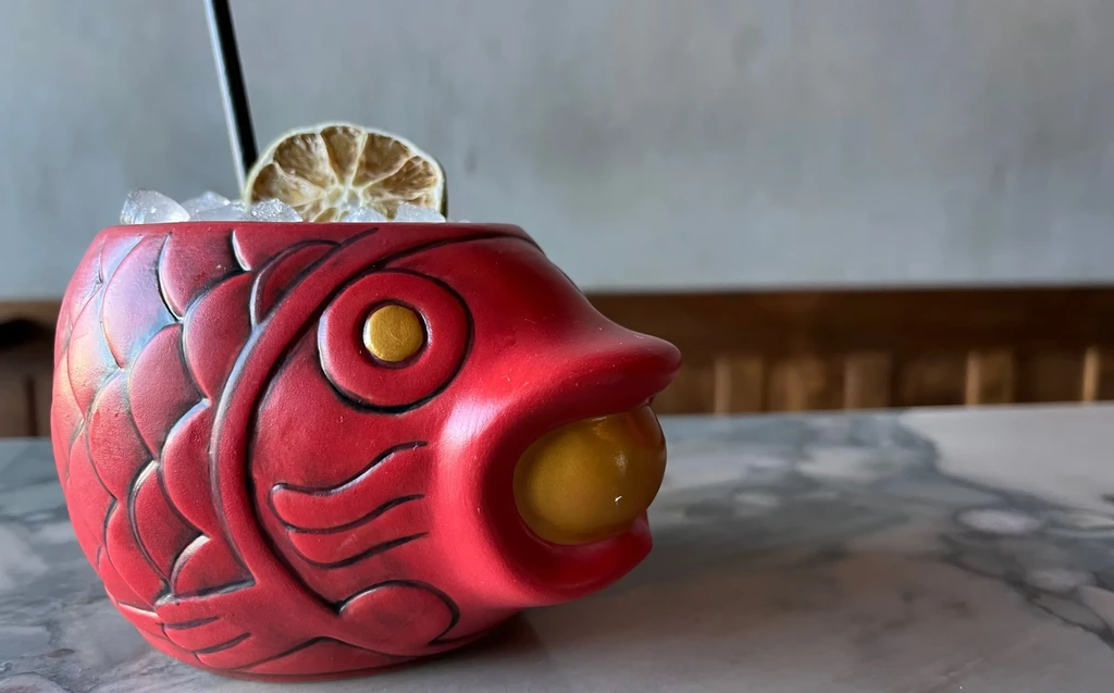 Red ceramic fish-shaped tiki mug filled with a cocktail and garnish.