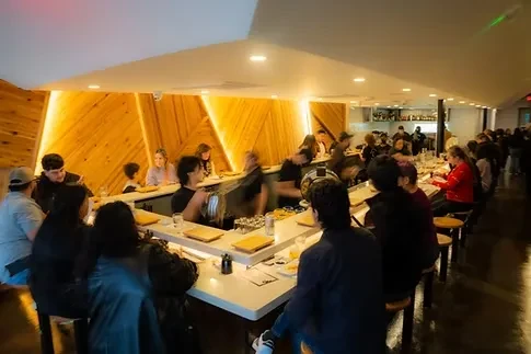 Restaurant interior with customers at a counter and staff working.