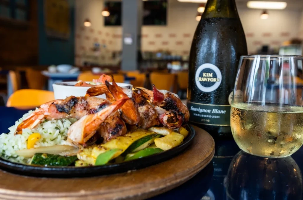 Grilled shrimp, bacon-wrapped chicken, rice, vegetables, and white wine.