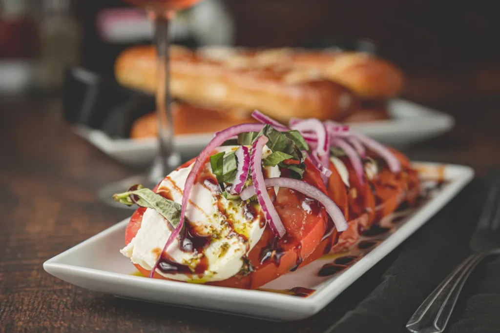 Caprese salad with tomatoes, mozzarella, basil, red onion, and balsamic.