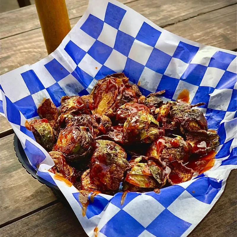 Roasted Brussels sprouts with reddish-brown sauce in a black basket.