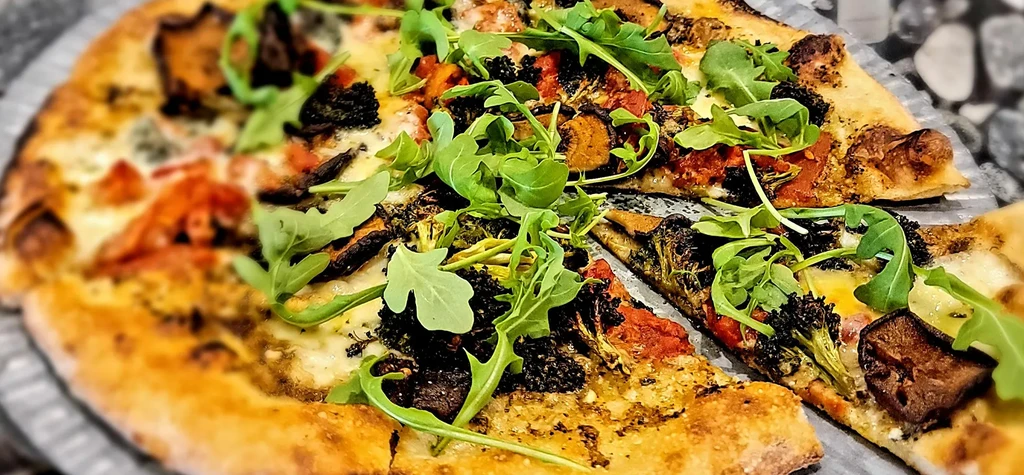 Overhead view of a partially eaten pizza with various vegetable toppings.