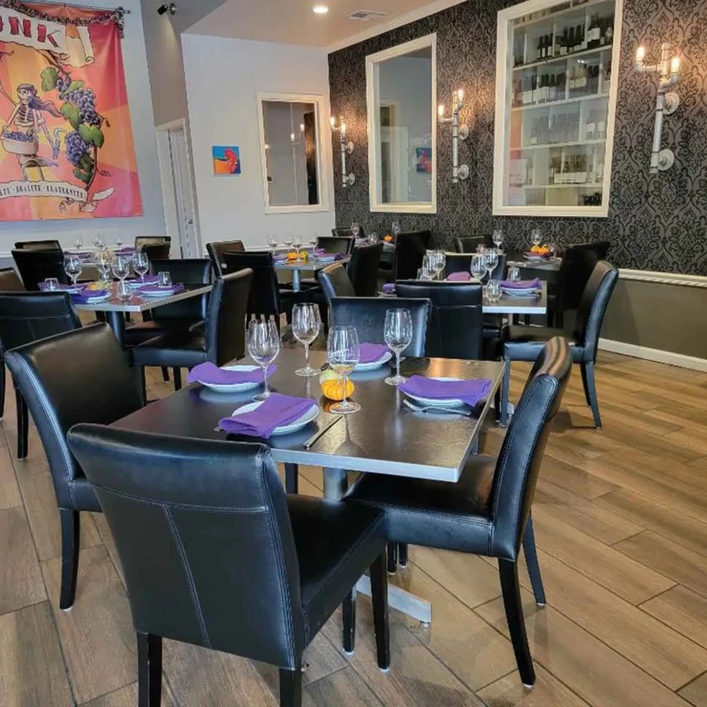 Elegant restaurant dining area with tables, damask wallpaper, and art.