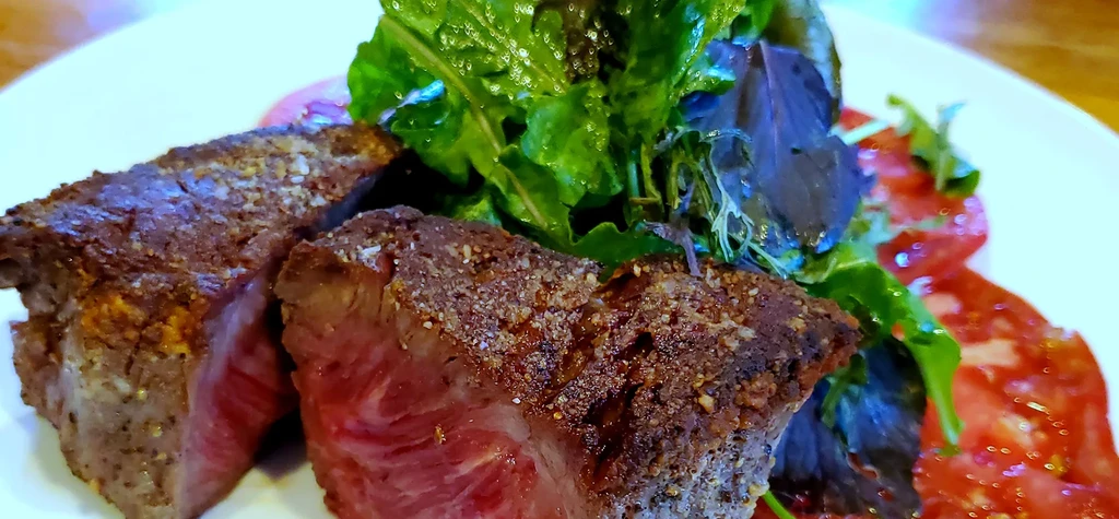 Plate with two medium-rare steaks and a side salad.