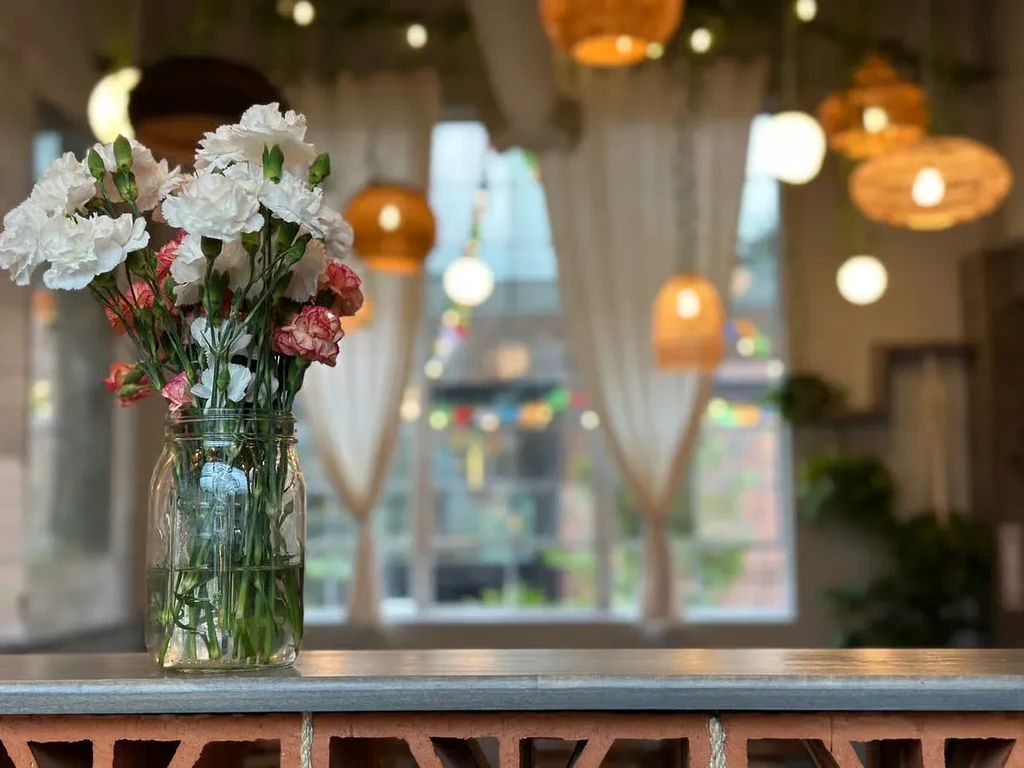 White and pink carnations in a mason jar on a gray countertop.