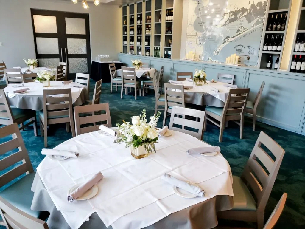 Restaurant dining room with set tables, floral centerpieces, and map art.