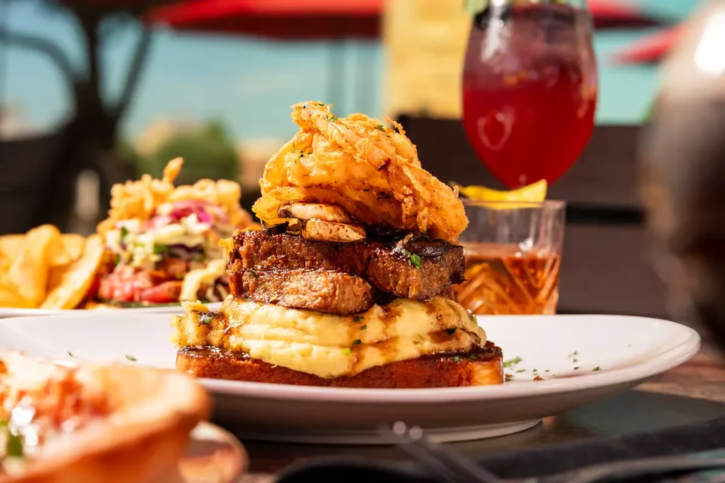 Open-faced sandwich with mashed potatoes, meat, mushrooms, and onion rings.