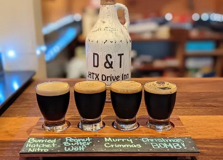 A flight of four dark beers on a paddle, with a growler.