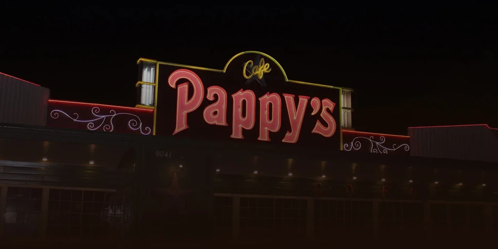 Neon sign for "Cafe Pappy's" on a dark building at night.