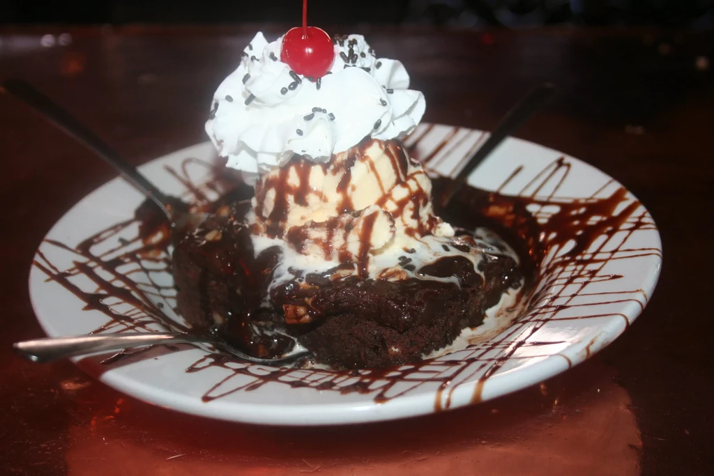 Chocolate brownie dessert with ice cream, whipped cream, and cherry.
