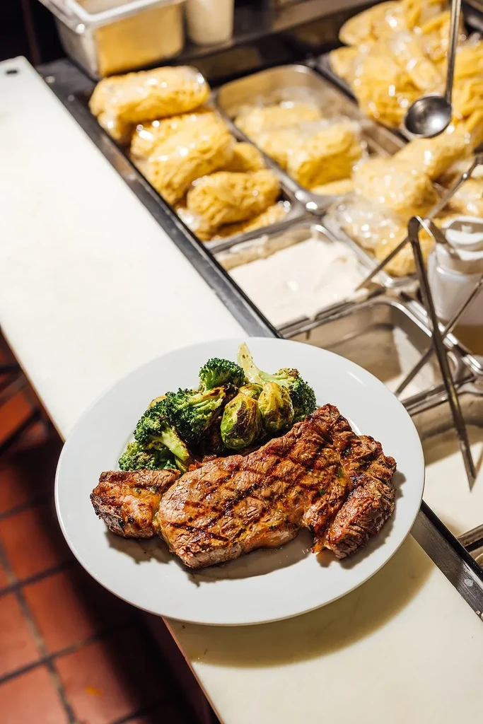 Grilled steak, roasted broccoli, and Brussels sprouts on a white plate.