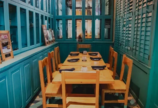 Restaurant dining area with a long wooden table and teal walls.