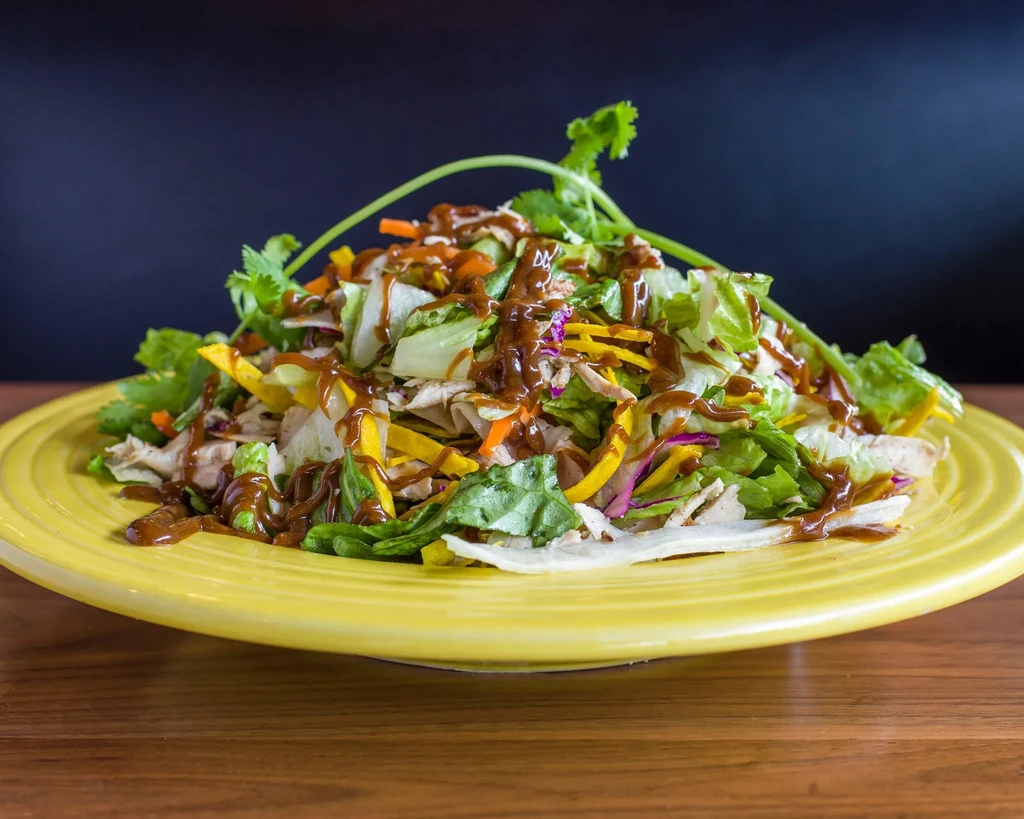 Salad with greens, carrots, cabbage, protein, and dark dressing.