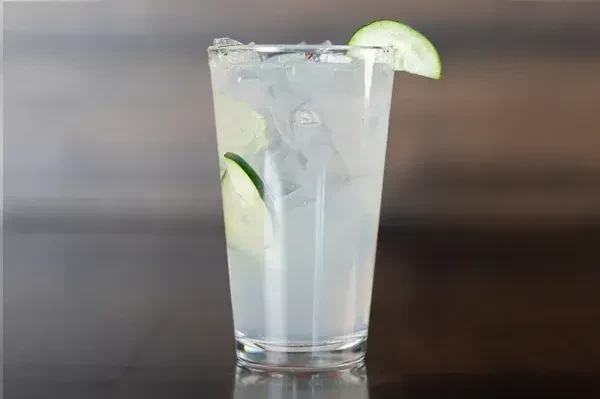 Clear glass with light drink, ice, and two cucumber slices.
