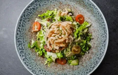 Top-down salad with lettuce, tomatoes, avocado/cucumber, and fried onions.