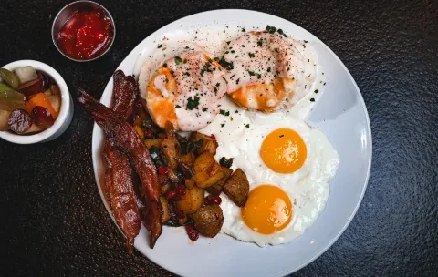 Overhead shot of a breakfast platter with eggs, bacon, potatoes.