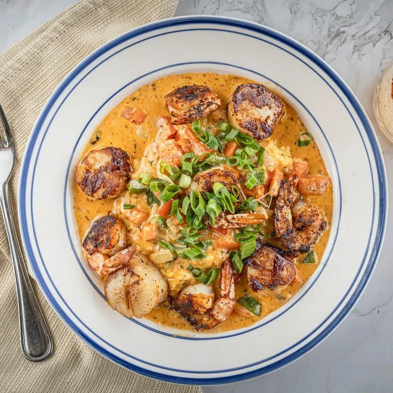 Overhead view of scallops and shrimp in an orange sauce.