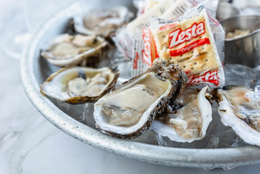 Raw oysters on ice, with Zesta Saltine Crackers packets.