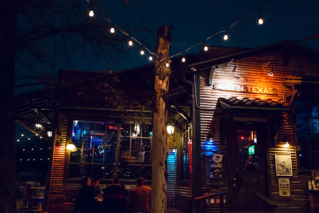 Night view of a rustic building with an "AUSTIN.TEXAS" neon sign.