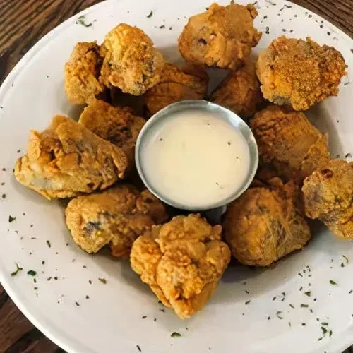 Close-up of fried food with dipping sauce on a white plate.