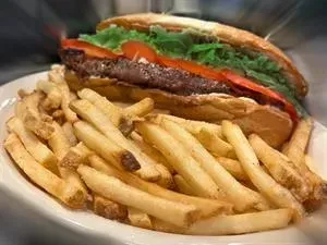 Submarine sandwich with a patty, lettuce, tomatoes, and golden french fries.