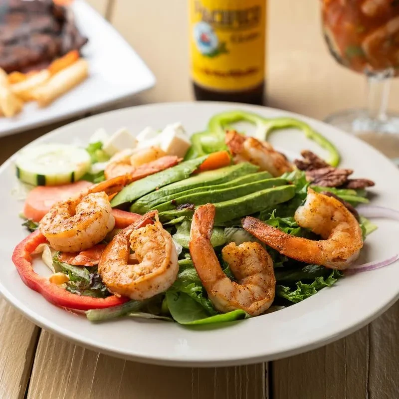 Shrimp and avocado salad on a white plate with a drink.